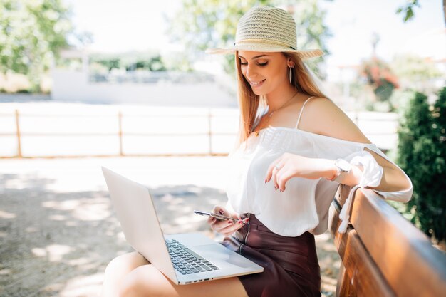 Computador portátil de mulher jovem e bonita no parque.