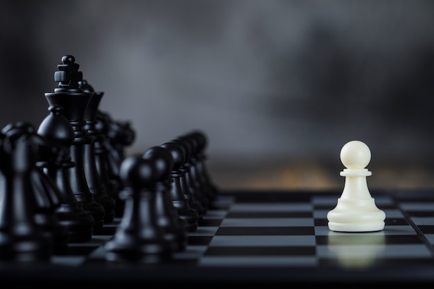Conceito da estratégia empresarial com figuras no tabuleiro de xadrez na opinião lateral da tabela nevoenta e de madeira.