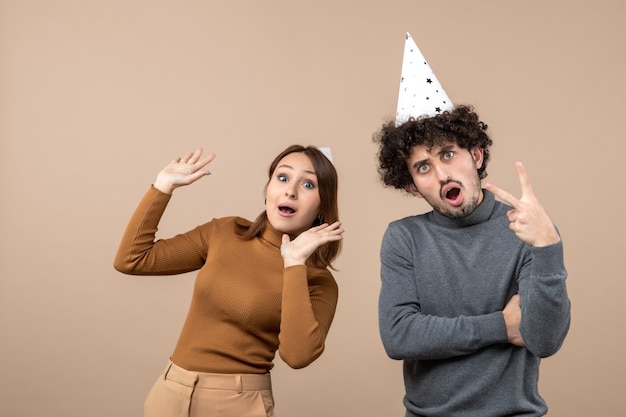 Conceito de ano novo com um casal jovem e adorável e feliz usando uma garota de chapéu de ano novo e um cara de cinza