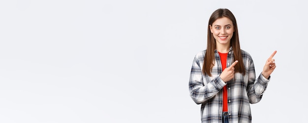 Foto grátis conceito de atividades de lazer de emoções diferentes de estilo de vida garota caucasiana atraente e amigável na camisa xadrez informar sobre novas promoções apontando os dedos para a direita e sorrindo a câmera