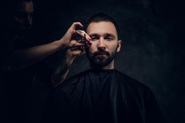 Conceito de barbearia - homem elegante recebe um corte de cabelo do cabeleireiro feminino.