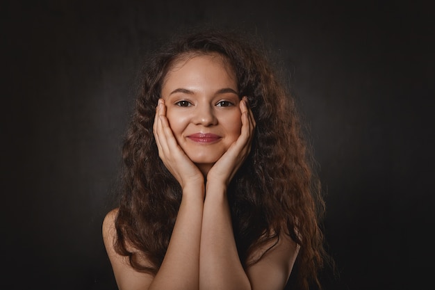 Conceito de beleza, alegria e felicidade. Retrato de uma jovem adorável e encantadora com o queixo nas mãos