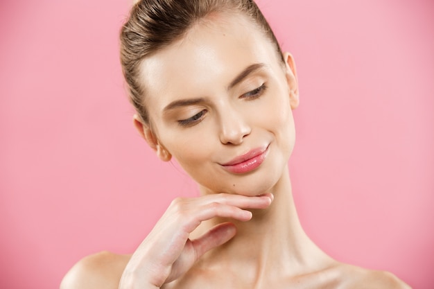 Conceito de beleza - Close up Retrato de garota caucasiano atraente com pele natural de beleza isolada no fundo rosa com espaço da cópia.