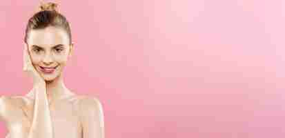 Foto grátis conceito de beleza mulher bonita com pele limpa e fresca perto do estúdio rosa rosto de cuidados com a pele cosmetologia