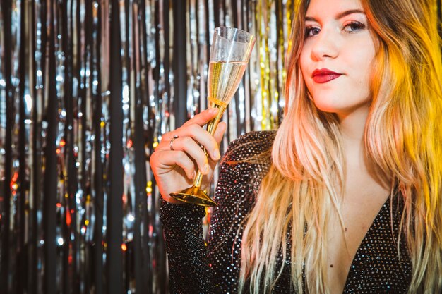 Conceito de celebração de ano novo com mulher loira segurando copo de champanhe