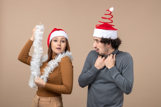 Conceito de clima festivo de ano novo com casal adorável satisfeito e animado, usando chapéu de papai noel vermelho na filmagem cinza