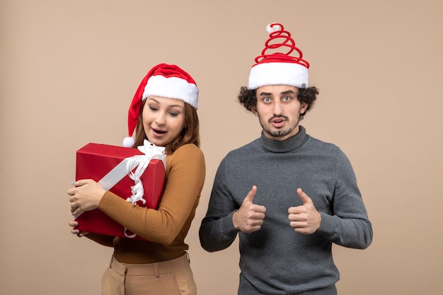 Conceito de clima festivo de ano novo com um casal adorável e engraçado usando chapéu de papai noel vermelho na filmagem cinza