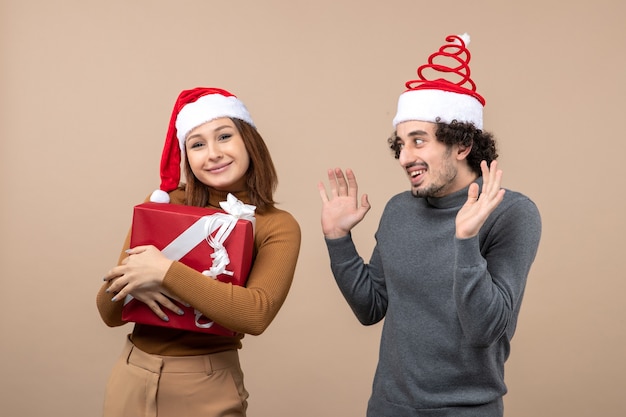 Conceito de clima festivo de ano novo com um casal adorável e engraçado usando chapéu de Papai Noel vermelho na filmagem cinza