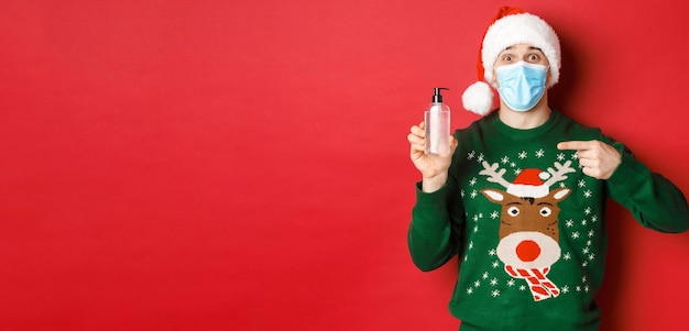 Conceito de coronavírus de ano novo e retrato de distanciamento social de homem alegre no chapéu de papai noel...