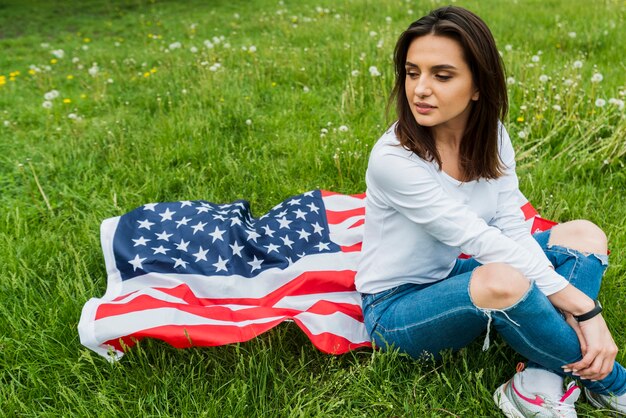 Conceito de dia da independência com mulher sentada e bandeira americana