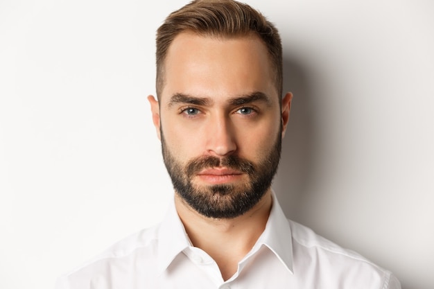 Foto grátis conceito de emoções e pessoas. foto de um homem bonito de aparência séria com barba, parecendo confiante e determinado