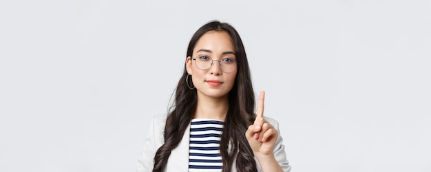 Conceito de empresárias bem-sucedidas de finanças e emprego closeup de gerente asiática de empresária elegante e inteligente explica a primeira regra de negócios mostrando um dedo e sorrindo