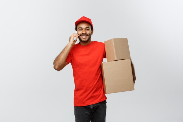 Conceito de entrega - Portrait of Handsome African American delivery man ou courier que mostra o tablet em você para verificar a ordem. Isolado no fundo do estúdio cinzento. Espaço de cópia.