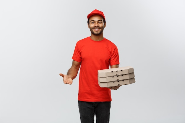 Conceito de entrega - Retrato de Handsome African American Pizza Delivery Man. Isolado no fundo do estúdio cinzento. Espaço de cópia.