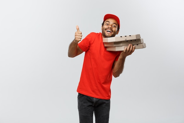 Foto grátis conceito de entrega - retrato de handsome african american pizza delivery man. isolado no fundo do estúdio cinzento. espaço de cópia.