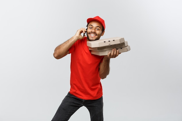 Conceito de entrega - retrato de handsome african american pizza delivery man. isolado no fundo do estúdio cinzento. espaço de cópia.