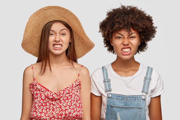 Conceito de expressões faciais negativas. Garotas interraciais irritadas cerram os dentes e franzem a testa em irritação