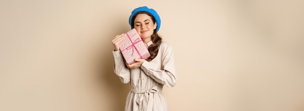 Foto grátis conceito de feriados e presentes linda garota recebe caixa de presentes e parece feliz segurando rosa embrulhado