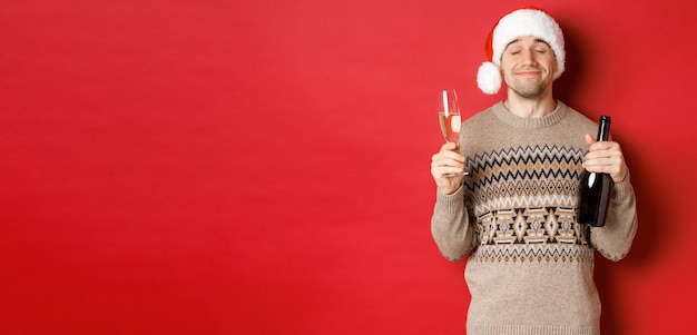 Conceito de férias de inverno, Natal e imagem de celebração do homem sorridente satisfeito com chapéu de Papai Noel e s ...