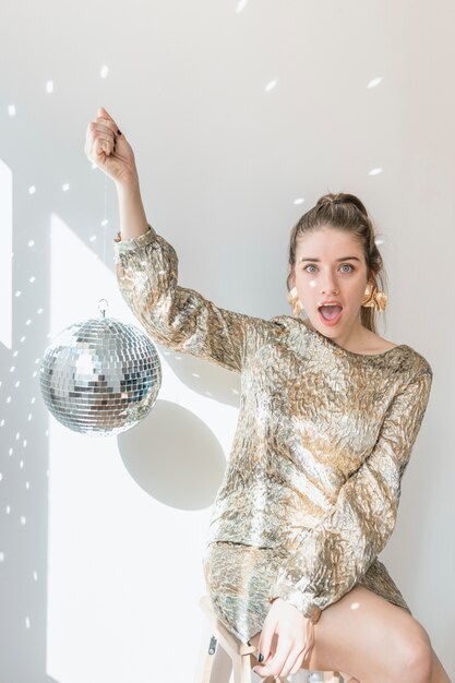 Conceito de festa de ano novo com garota segurando bola de discoteca