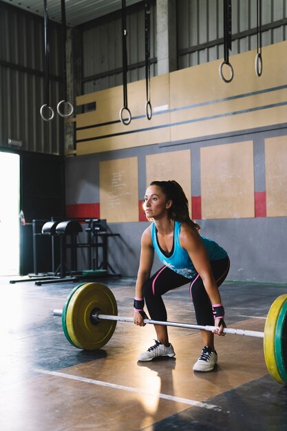 Conceito de fitness com mulher prestes a levantar barbell