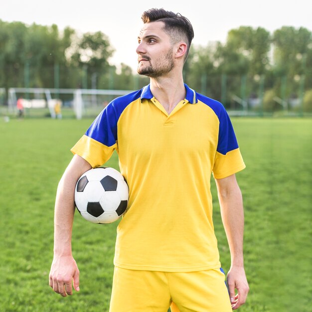 Conceito de futebol amador com homem posando com bola