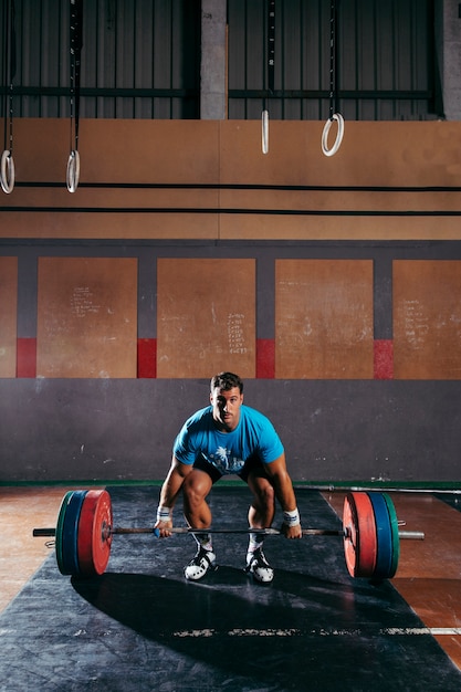 Foto grátis conceito de ginásio com o homem prestes a levantar barbells