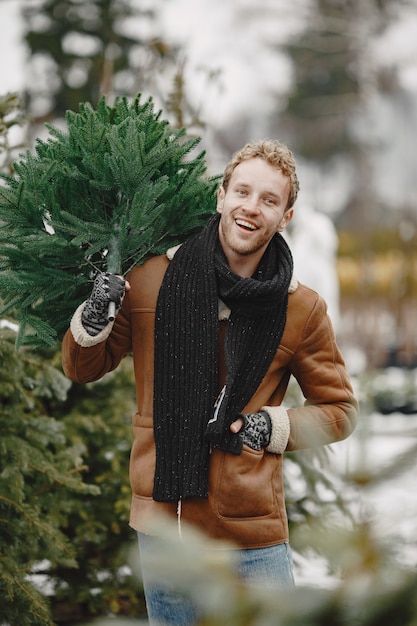 Conceito de inverno. Cara com um casaco marrom. Vendedor de Árvore de Natal.