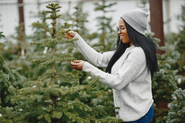 Conceito de inverno. Mulher com um suéter cinza. Vendedora de árvore de Natal.