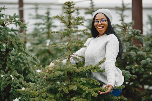 Foto grátis conceito de inverno. mulher com um suéter cinza. vendedora de árvore de natal.