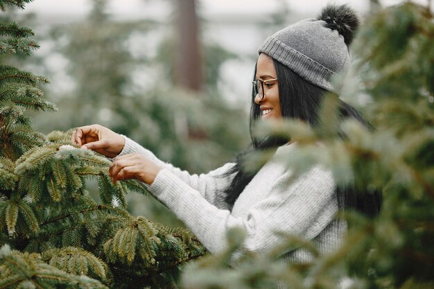 Conceito de inverno. Mulher com um suéter cinza. Vendedora de árvore de Natal.