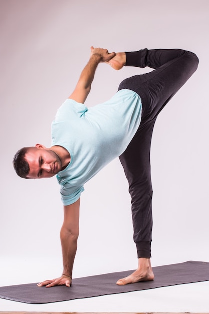 Conceito de ioga. Homem bonito fazendo exercícios de ioga isolado em um fundo branco