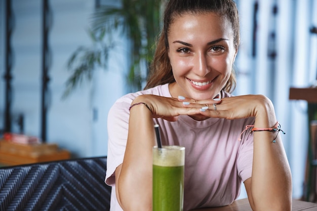 Foto grátis conceito de lazer de datas românticas mulher adulta atraente, inclinar-se sobre as mãos, olhando coquete em seus olhos, sorrindo enquanto sentam juntos no café, bebida, smoothie, nas férias da ilha tropical, viagens ao redor do mundo