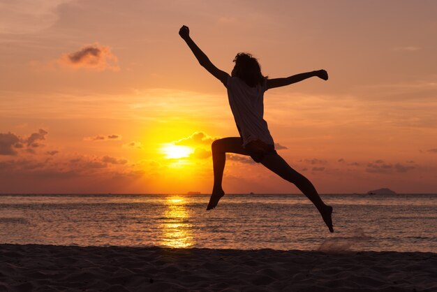 Conceito de liberdade com jovem adolescente feliz e pular na praia