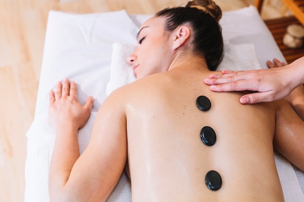 Conceito de massagem com pedras nas costas da mulher
