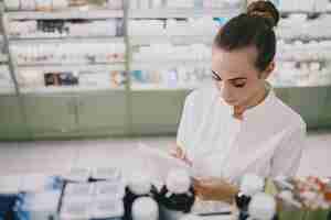 Foto grátis conceito de medicina, farmacêutica, saúde e pessoas. farmacêutico feminino tomando medicamentos da prateleira.