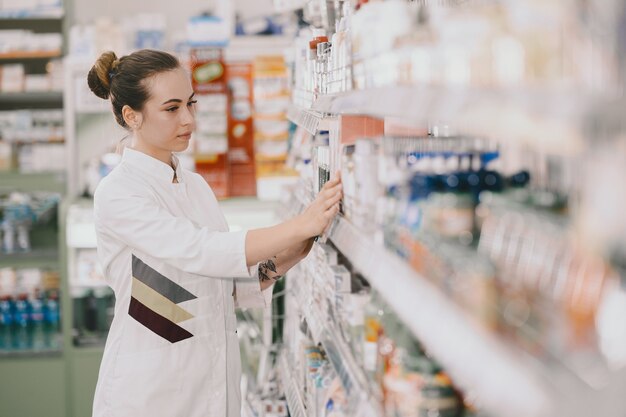 Conceito de medicina, farmacêutica, saúde e pessoas. Farmacêutico feminino tomando medicamentos da prateleira.