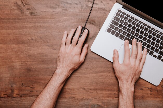 Conceito de mesa de trabalho com mãos trabalhando no laptop