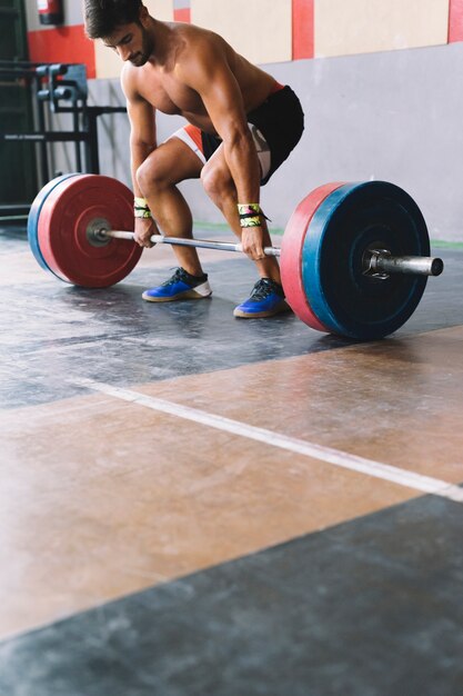 Conceito de musculação com homem forte prestes a levantar barbell