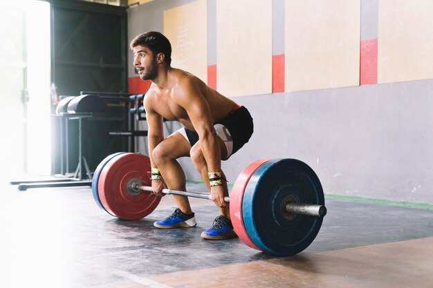 Conceito de musculação com homem prestes a levantar barbell