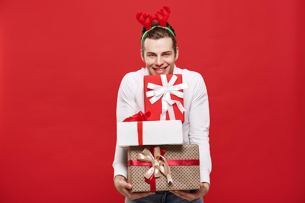 Conceito de natal bonito empresário caucasiano feliz segurando muitos presentes com chapéu de papai noel posando em fundo branco isolado