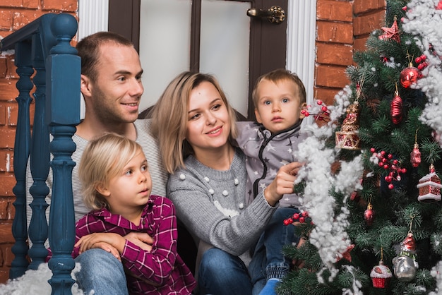 Conceito de natal com a família sentada fora com árvore de natal