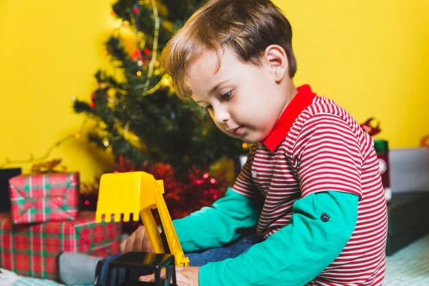 Conceito de Natal com criança brincando na frente da árvore de Natal