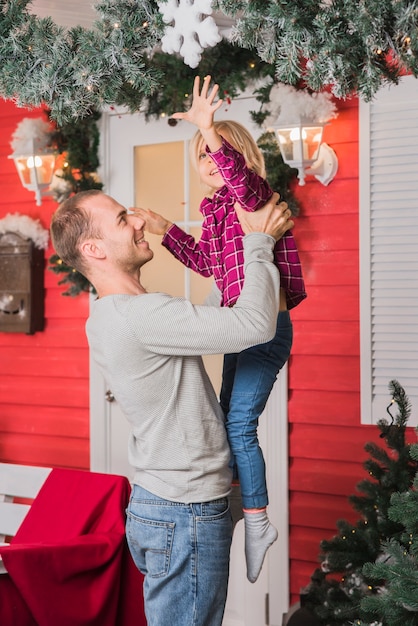 Conceito de Natal com o pai feliz, levantando a filha