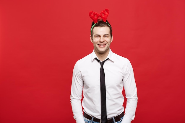 Conceito de Natal Homem de negócios bonito comemora feliz natal e feliz ano novo usa faixa de cabelo de rena e segurando a mão no bolso