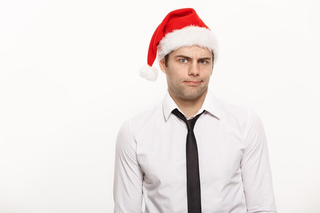 Conceito de Natal Homem de negócios bonito usa chapéu de Papai Noel posando com expressão facial pensativa em fundo branco isolado