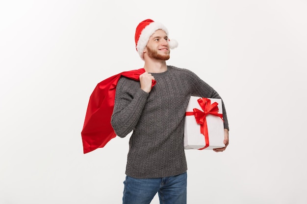 Conceito de Natal Jovem homem de barba feliz segurando saco de papai noel e presente branco