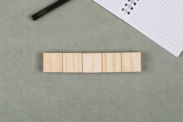 Foto grátis conceito de negócio com cubos de madeira, caderno, caneta na configuração de plano de fundo cinza.