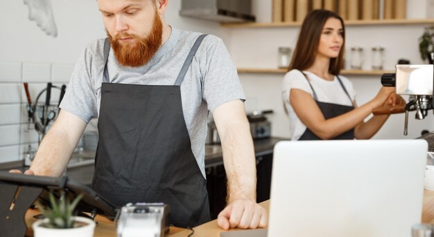 Conceito de negócio de café Jovem barman barbudo bonito ou gerente postando o pedido do convidado no menu de tablet digital no café moderno