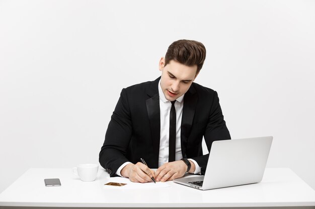 Conceito de negócio: retrato concentrado jovem empresário de sucesso escrevendo documentos na brilhante mesa de escritório.